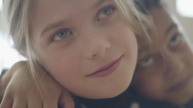 Close-up portrait face of a beautiful little caucasian girl who is embraced by an adorable African American boy.