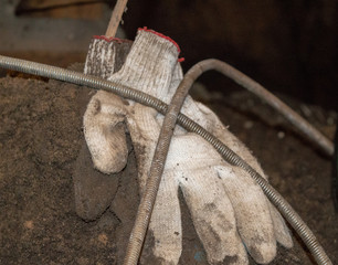 gloves for work on a pile of sand surrounded by a rope for cleaning of sewers