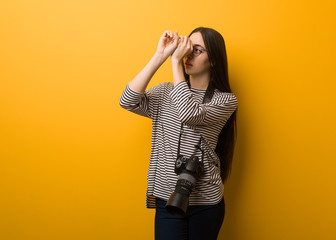 Young photographer woman making the gesture of a spyglass