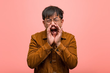 Young chinese man wearing a jacket shouting something happy to the front