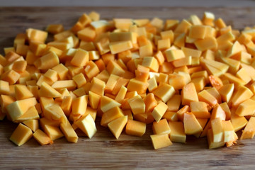 Chopped butternut squash on wooden cutting board. Selective focus.
