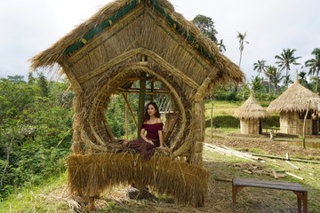 mujer sentada en una casa hecha de paja