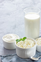 Organic cottage cheese in bowl, sour cream and milk on blue napkin. Gray background.