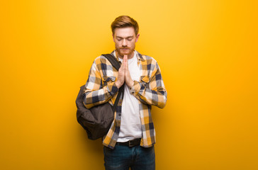 Young redhead student man praying very happy and confident