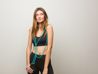 Young fitness russian woman dreaming of achieving goals and purposes. Holding a jump rope.