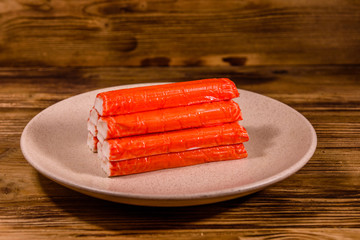 Ceramic plate with pile of crab sticks on a wooden table