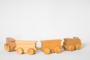 wooden toy locomotive with three wagons, against white background. Copy space
