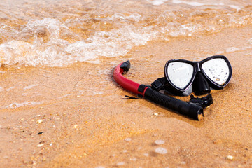 Black mask and red tube on the beach. Gear for diving close up.