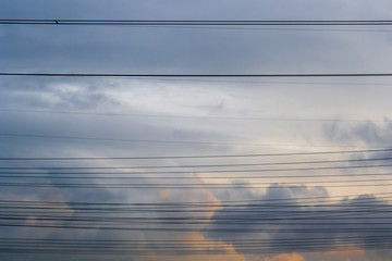 Multiple horizontal high voltage cable lines across stormy clouds, at sunset. Simple concept for power/electricity distribution and connectivity.