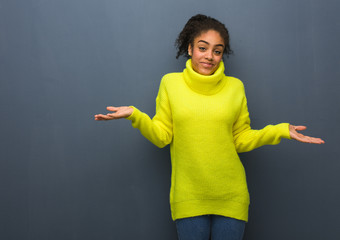 Young black woman doubting and shrugging shoulders
