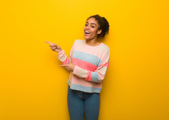 Young black african american girl with blue eyes pointing to the side with finger