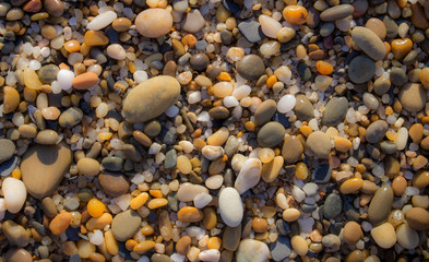 Colorful pebbles on beach. Pebbles closeup background. Small round stones in sunlight. Minerals concept. Sea shore background. Pebbles wallpaper. 