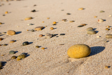 Colorful pebbles on sand. Round stones on the beach. Peaceful concept. Nature details. Coast nature. Ocean pebbles with unfocused background.