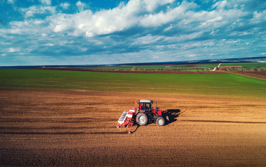 Farmer with tractor seeding crops at field