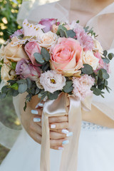 the bride is holding a wedding bouquet. fine art style. light pink roses