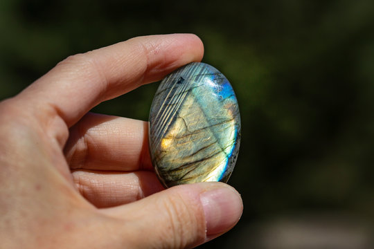 Labradorite stone kaboshon shining in female hand