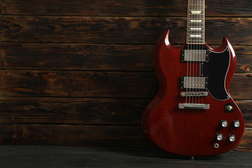 Fototapeta premium Beautiful six - string electric guitar against wooden background, space for text