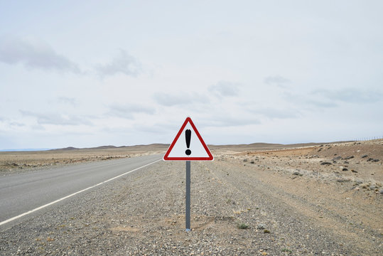 Argentina, Patagonia, Empty road with exclamation mark sign in the middle of desert