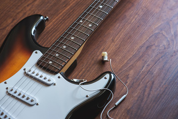 Electric guitar, headphones on the wooden background,