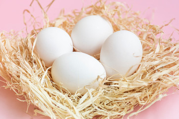 White chicken eggs in hay nest.