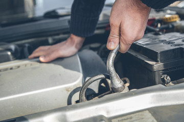 Mechanic hand checking and fixing a broken car in car service garage