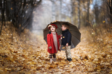 boy and girl children under umbrella in autumn