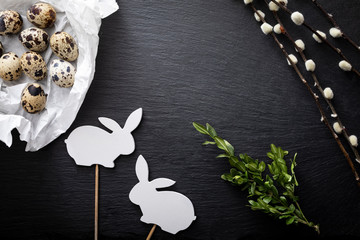 Easter background.  Natural quail eggs, willow branches and easter bunny on a dark background