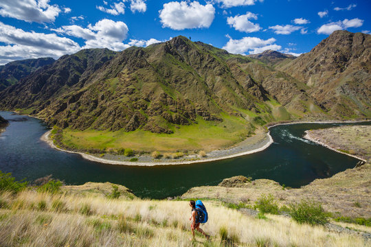 A female backpacker on the scenic Snake River National Recreation Trail (#102) in Hells Canyon along the Oregon-Idaho border. The canyon is the deepest river gorge in North America with more than a mile of vertical elevation between the river floor and nearby peaks in the Seven Devil Mountains.