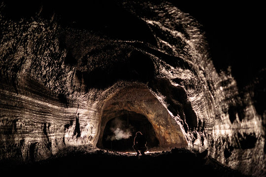 A male caver holding a propane lantern while exploring the 13,042 foot long Ape Cave near Mount St. Helens in the Gifford Pinchot National Forest of western Washington State. The cave is the third longest known lava tube in North America. The cave is open year round and has a easier, shorter lower cave section and a slightly more physical and longer upper cave section.