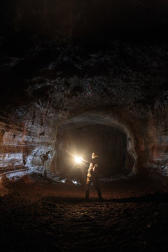 A male caver holding a propane lantern while exploring the 13,042 foot long Ape Cave near Mount St. Helens in the Gifford Pinchot National Forest of western Washington State. The cave is the third longest known lava tube in North America. The cave is open year round and has a easier, shorter lower cave section and a slightly more physical and longer upper cave section.