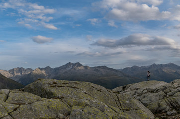 Fototapeta premium A girl on hiking trip in Swiss Alps enjoys the view down to the valley on the background of mountain ridge