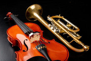A new shining violin and an old trumpet on a dark table. Musical instruments, stringed and wind.
