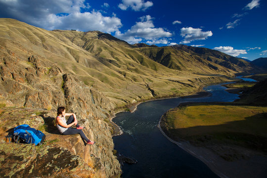 A female backpacker at the 400-foot Suicide Point along the scenic Snake River National Recreation Trail (#102) in Hells Canyon along the Oregon-Idaho border. The canyon is the deepest river gorge in North America with more than a mile of vertical elevation between the river floor and nearby peaks in the Seven Devil Mountains.