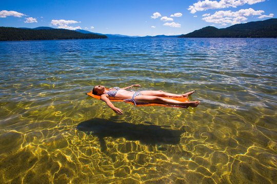 A woman escapes the summer heat by floating on inflatable Thermarest sleeping pads at a swimming area near Reeder Bay Campground on the west end of the pristine and beautiful Priest Lake in north Idaho.