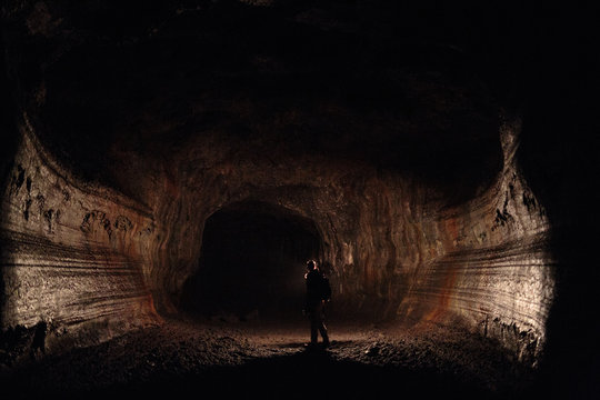 A male caver holding a propane lantern while exploring the 13,042 foot long Ape Cave near Mount St. Helens in the Gifford Pinchot National Forest of western Washington State. The cave is the third longest known lava tube in North America. The cave is open year round and has a easier, shorter lower cave section and a slightly more physical and longer upper cave section.