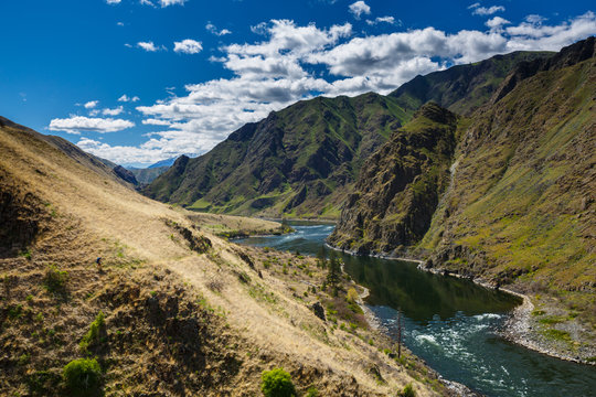 A tiny female backpacker hikes along the scenic Snake River National Recreation Trail (#102) along the Oregon-Idaho border. The canyon is the deepest river gorge in North America with more than a mile of vertical elevation between the river floor and nearby peaks in the Seven Devil Mountains.     