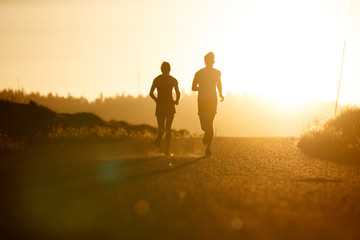 Silhouette of woman and man running at sunset