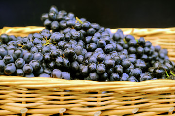 Branches of grapes in a wicker basket. Bundles of fresh ripe red grapes in the grocery store, selective focus. Grape background.