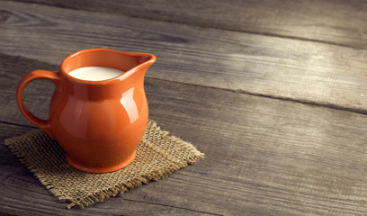 Milk in glass pitcher on white background wooden table