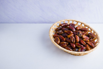Fototapeta na wymiar Dried dates on white background. Holy month of Ramadan, concept. Righteous Muslim lifestyle. Starvation. Dates in wooden basket. Vegetarian food. Copy space