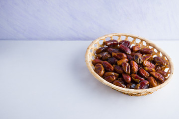Dried dates on white background. Holy month of Ramadan, concept. Righteous Muslim lifestyle. Starvation. Dates in wooden basket. Vegetarian food. Copy space