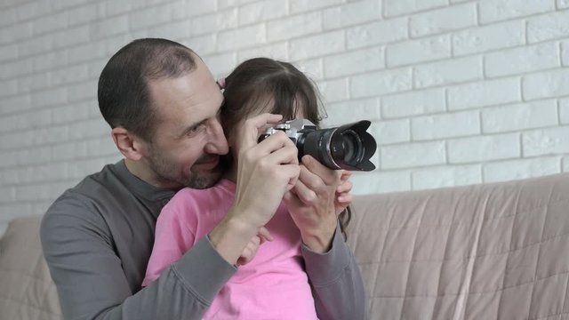 A man teaches daughter to photograph. Father and daughter take pictures together with a camera.