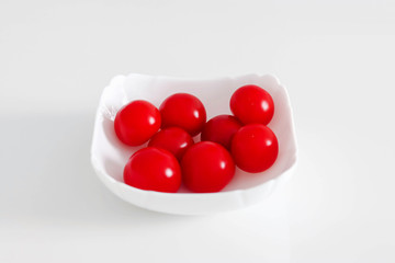 Fresh cherry tomatoes in a white plate, on a white background, White and Red Concept