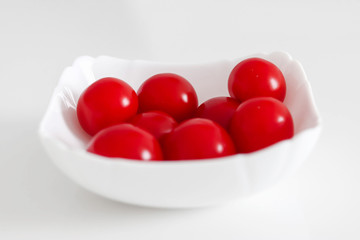 Fresh cherry tomatoes in a white plate, on a white background, White and Red Concept