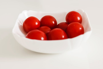 Fresh cherry tomatoes in a white plate, on a white background, White and Red Concept