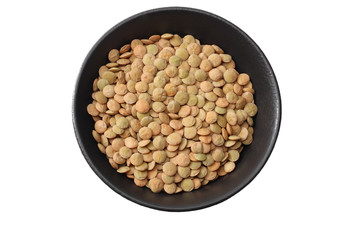 Pile lentil in black bowl isolated on white background. Top view.
