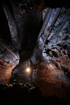 A male caver holding a propane lantern while exploring the 13,042 foot long Ape Cave near Mount St. Helens in the Gifford Pinchot National Forest of western Washington State. The cave is the third longest known lava tube in North America. The cave is open year round and has a easier, shorter lower cave section and a slightly more physical and longer upper cave section.
