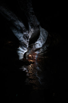 A male caver holding a propane lantern while exploring the 13,042 foot long Ape Cave near Mount St. Helens in the Gifford Pinchot National Forest of western Washington State. The cave is the third longest known lava tube in North America. The cave is open year round and has a easier, shorter lower cave section and a slightly more physical and longer upper cave section.