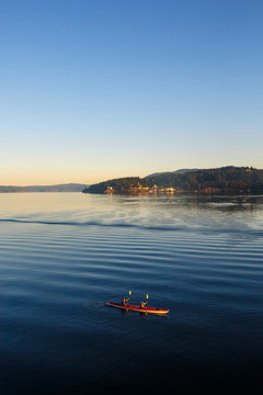 Two tandem kayakers paddle into the early morning light near Harney Channel while on a 3-day sea kayaking trip in the San Juan Islands. The photo was taken from Blind Island, a small 3 acre state park near Shaw Island that offers camping opportunities to human and wind-powered boats.