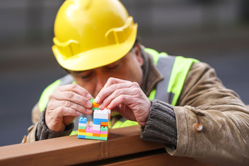 Concentrated civil engineer using multicoloured plastic construction toy building blocks or toy...